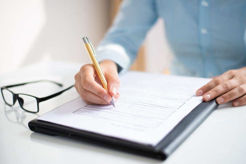 Closeup of business woman making notes in document. Entrepreneur sitting at desk and writing. Paperwork concept. Cropped view.
