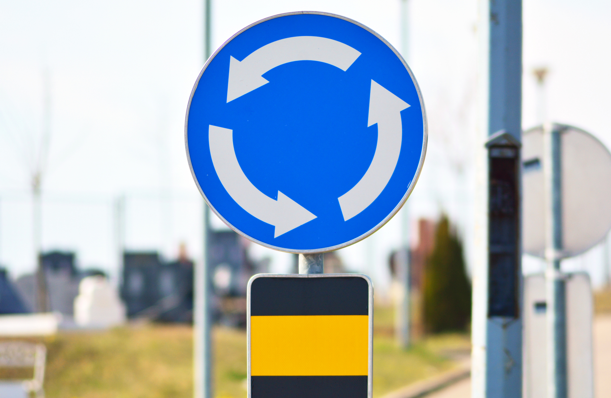 a blue roundabout traffic sign on a post